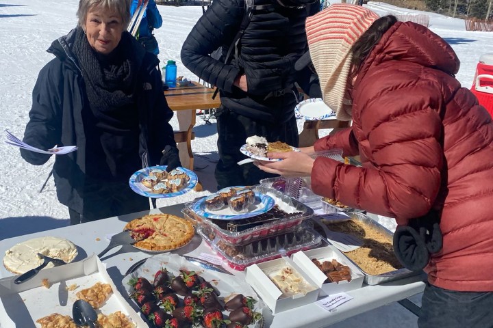 a group of people standing around a table eating food